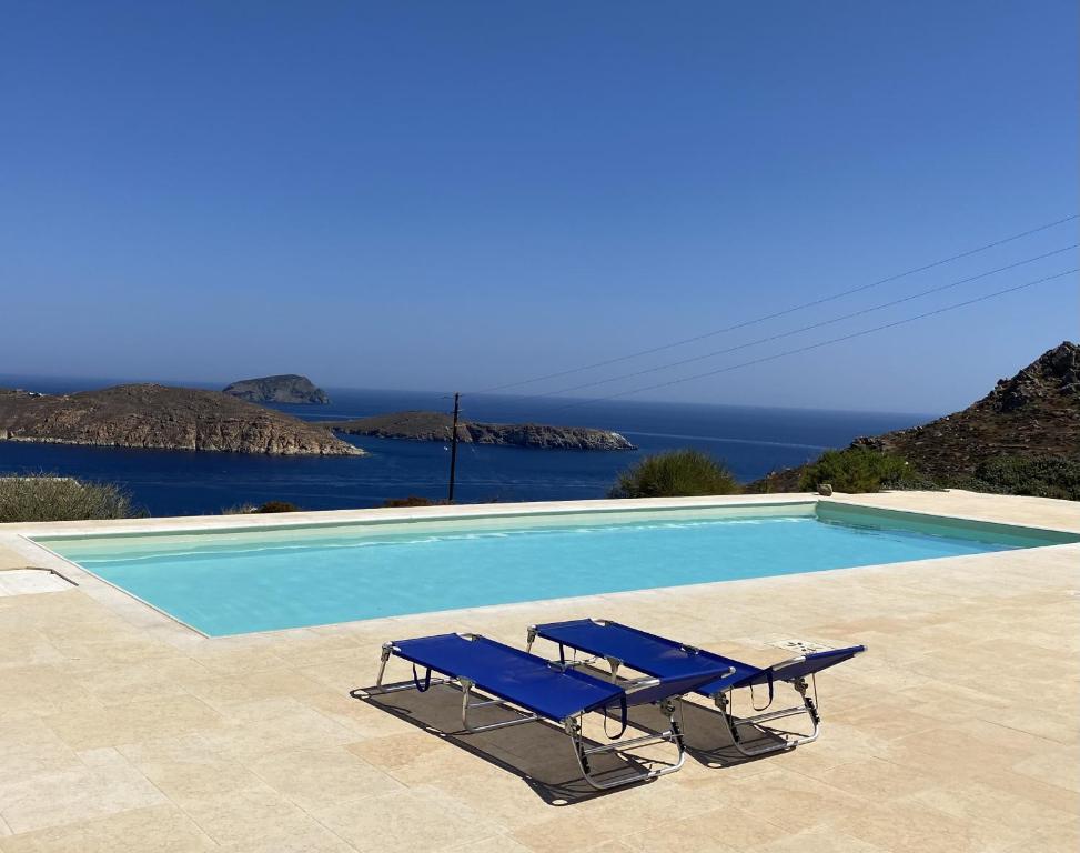 a swimming pool with two blue lounge chairs next to it at Serifos Stone Villa B in Rámos