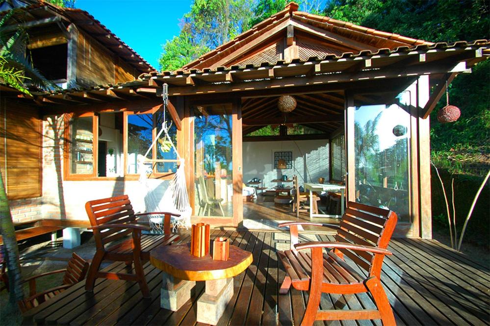 a wooden deck with chairs and a table and a house at Casa Vista al Mar in Morro de São Paulo