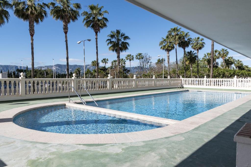 uma piscina com uma cerca branca e palmeiras em Nereo, 10º-45 em Cullera