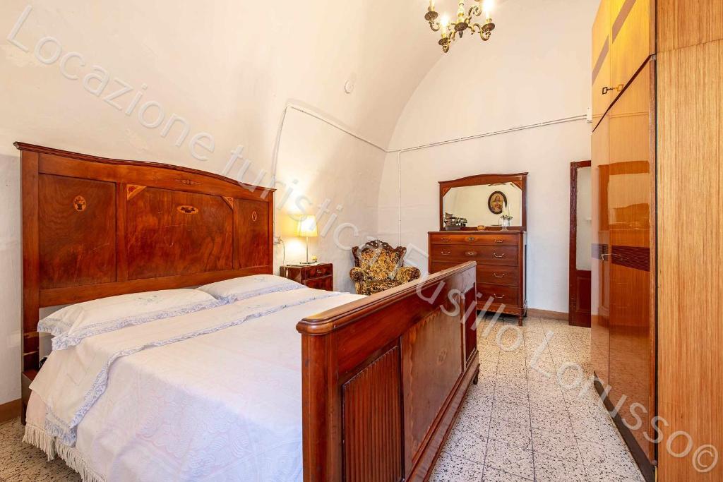 Locazione turistica Lorusso 1 في أندريا: غرفة نوم مع سرير خشبي كبير ومرآة