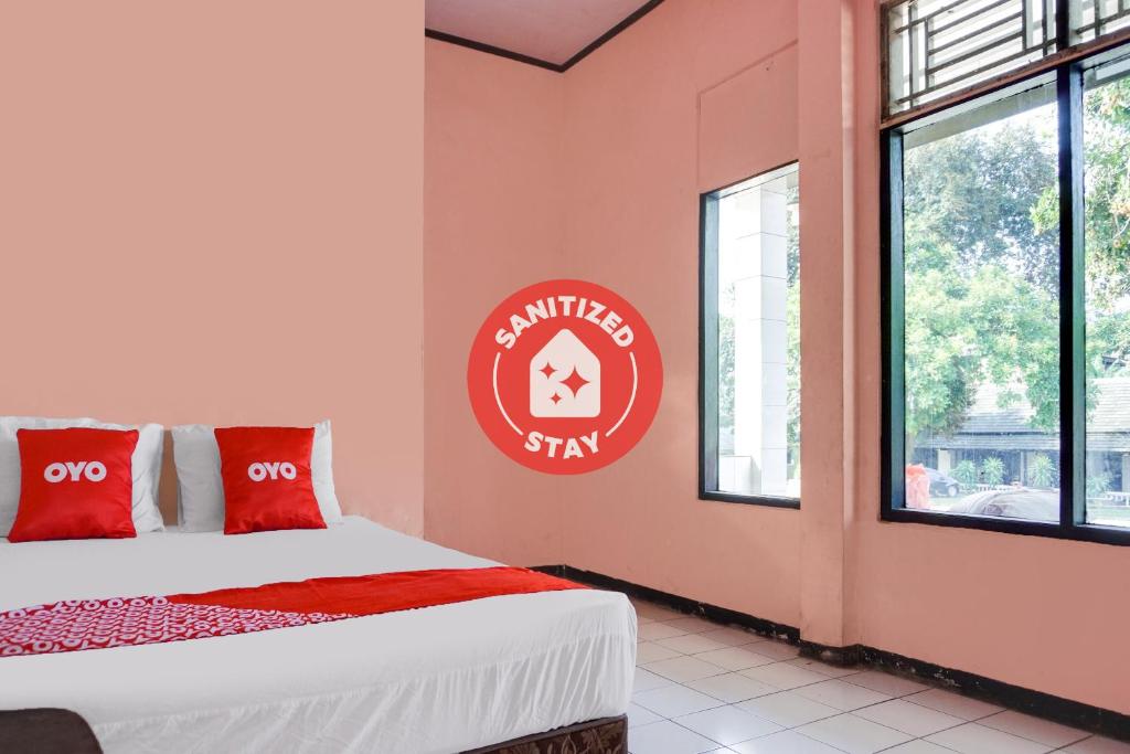 a room with a bed and a sign on the wall at SPOT ON 91797 Mutiara Guest House in Karawang