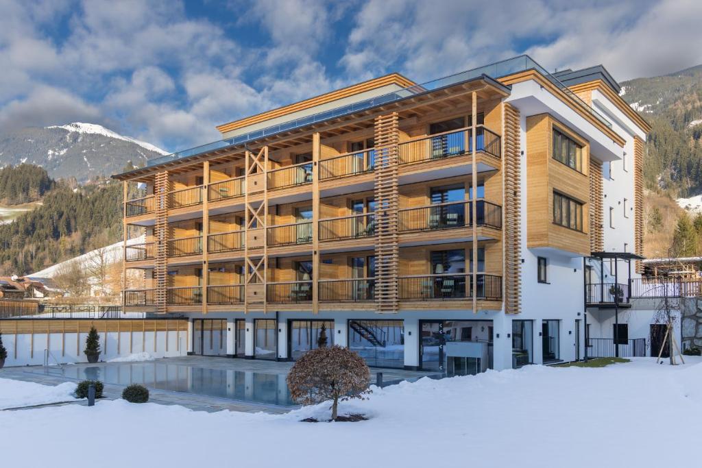 een groot gebouw met een zwembad in de sneeuw bij Natur Resort RISSBACHER in Stumm
