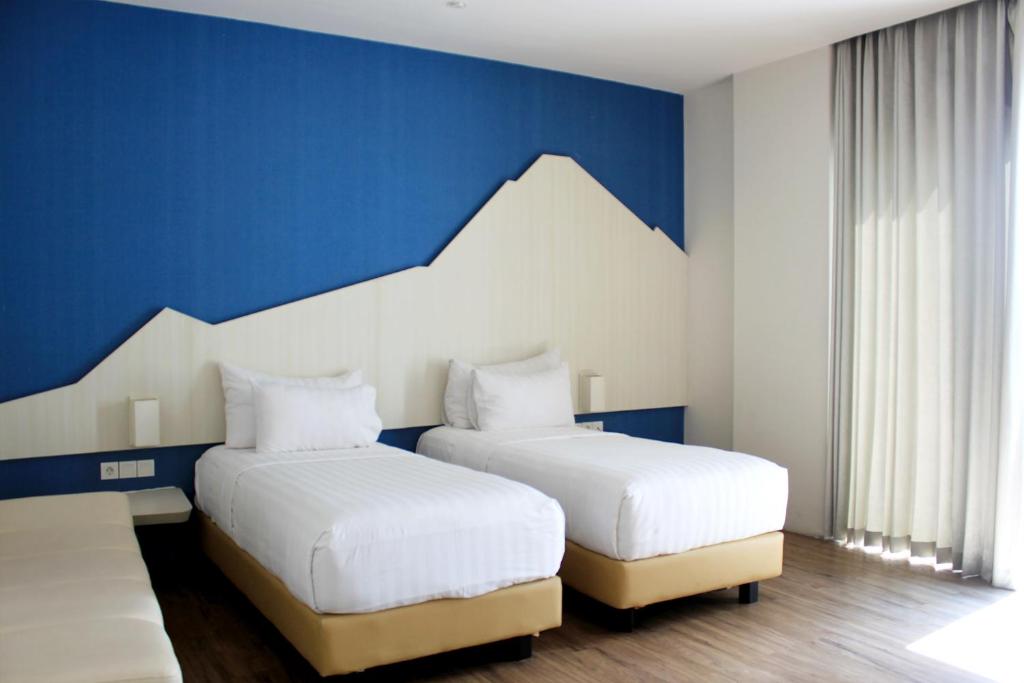 two beds in a room with blue and white walls at Bromo Park Hotel Probolinggo in Probolinggo