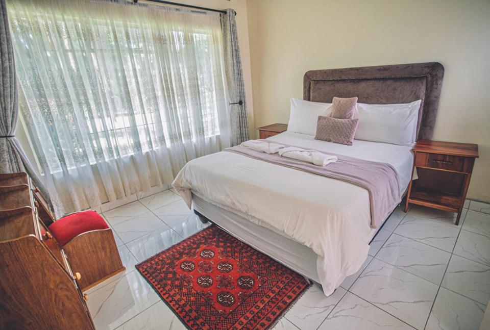 a bedroom with a large bed and a window at Palm villa in Harare