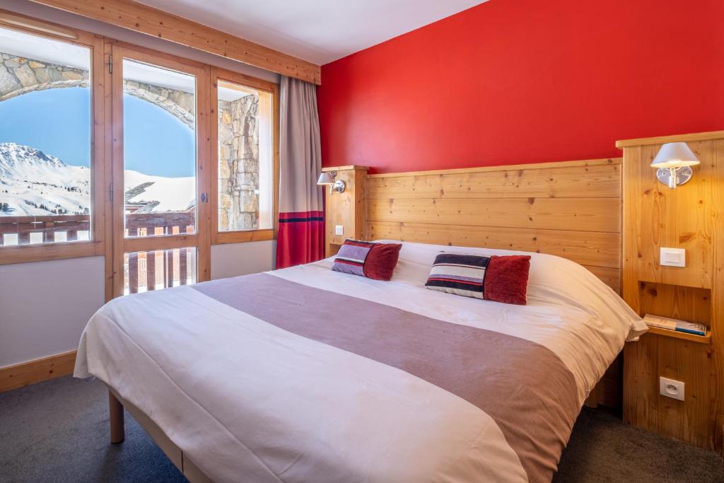 a bedroom with a large bed with a red wall at Résidence Pierre &amp; Vacances Les Néréides in Belle Plagne