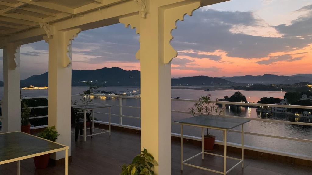 balkon ze stołami i widokiem na wodę w obiekcie Peacock Paying Guest House w mieście Udaipur