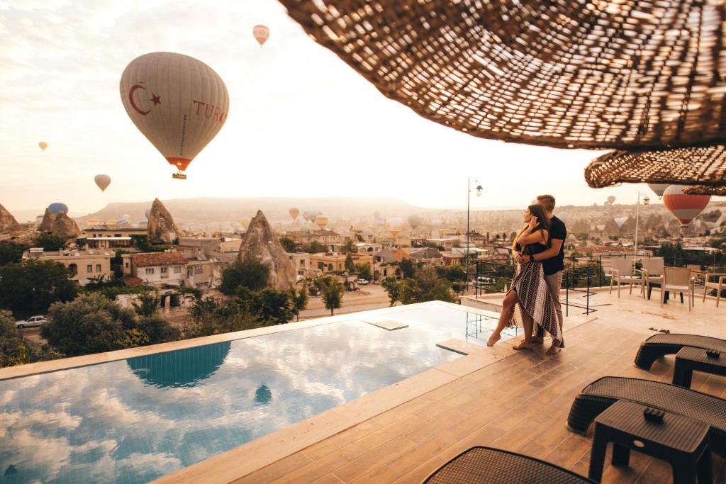 um homem e uma mulher de pé numa varanda com um balão de ar quente em Doors Of Cappadocia Hotel em Goreme