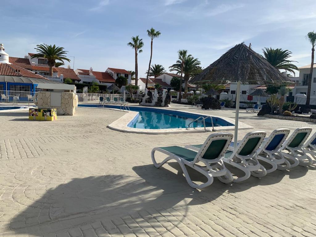 a group of lounge chairs next to a swimming pool at Eagle Studio in San Miguel de Abona