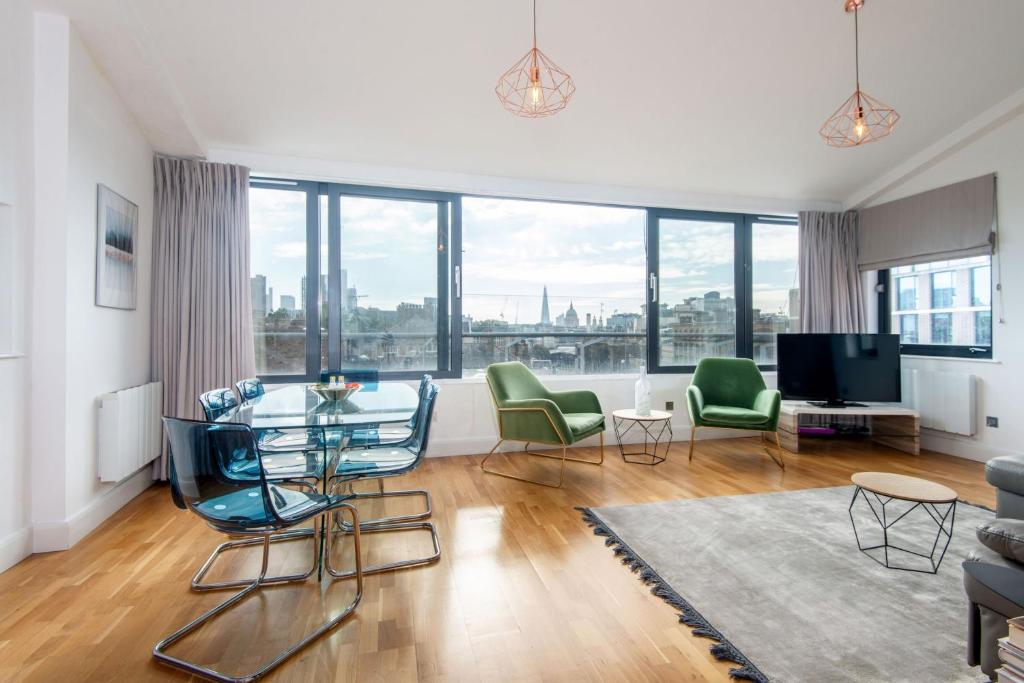 a living room with a glass table and green chairs at Mulberry South Penthouse by City Living London in London