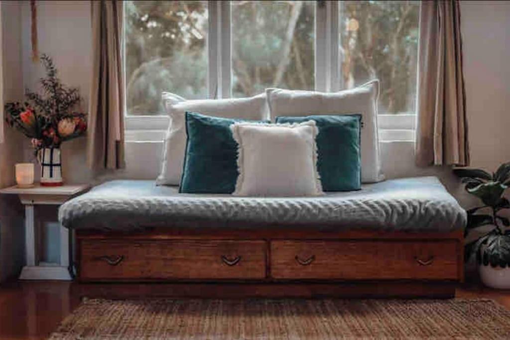 a bed with pillows on it in front of a window at Woodlands by the Sea in Port Campbell