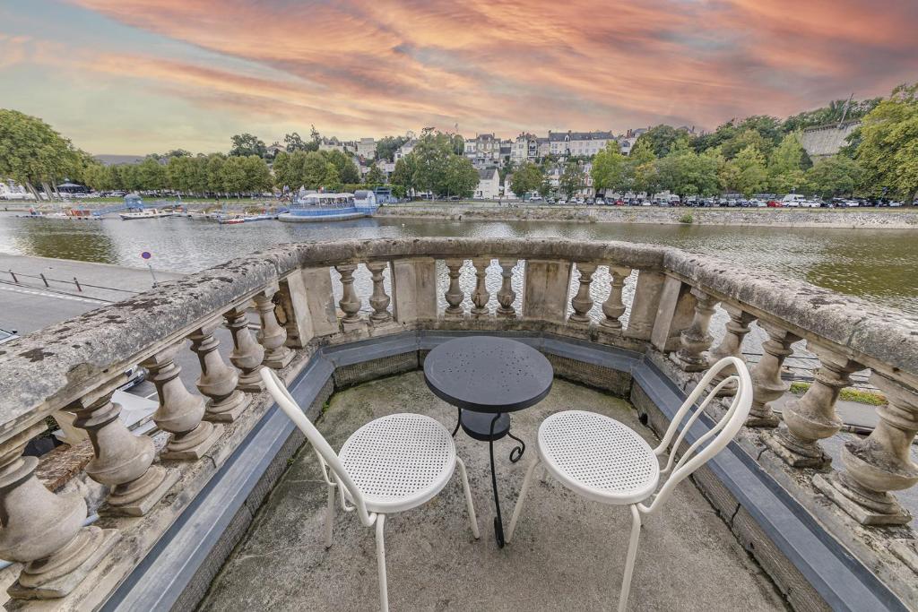 une table et des chaises assises sur un balcon à côté d'une rivière dans l'établissement Le Béatrix - Studio vue sur la Mayenne, à Laval