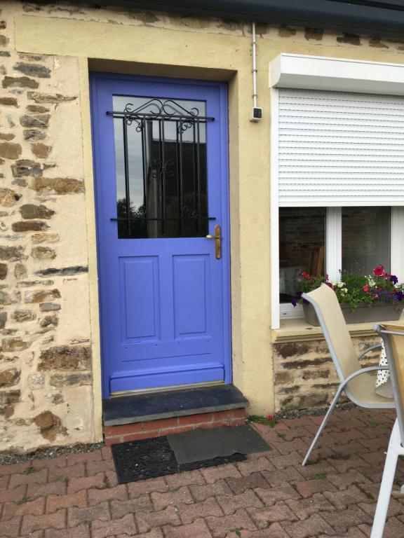 niebieskie drzwi na domu ze stołem i krzesłami w obiekcie La Morinais w mieście Éancé