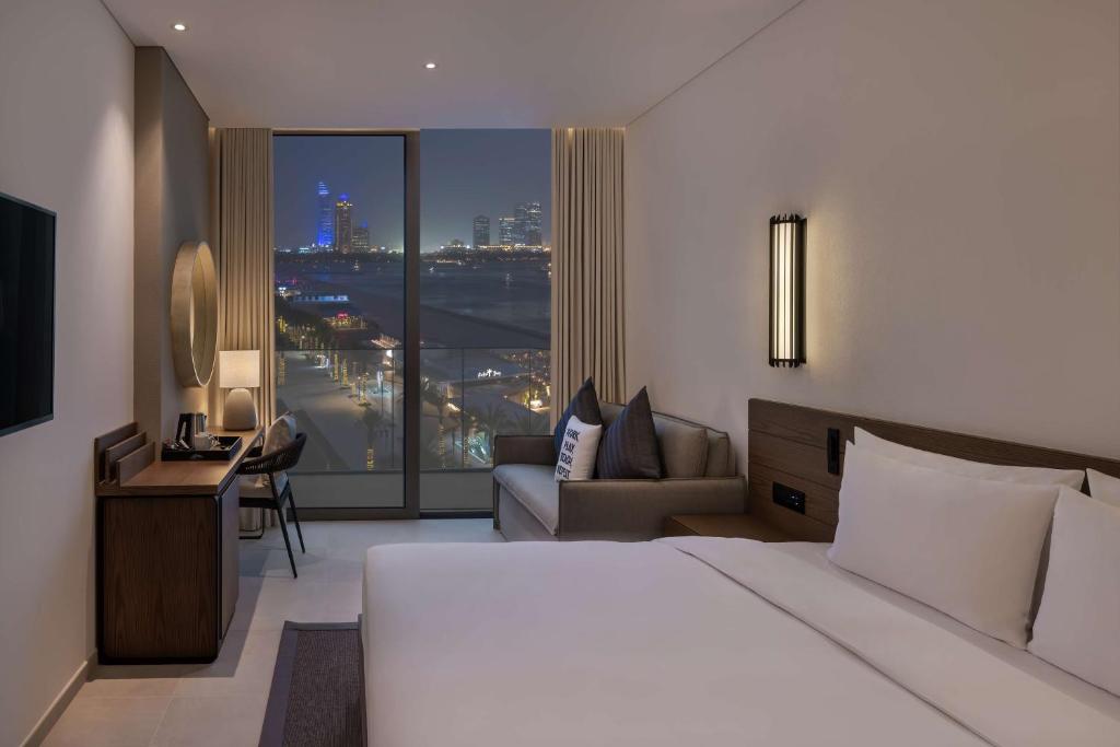 a hotel room with a bed and a large window at Radisson Beach Resort Palm Jumeirah in Dubai