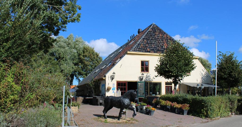 uma estátua de um cão preto em frente a uma casa em De Oude Smidse em Westernieland