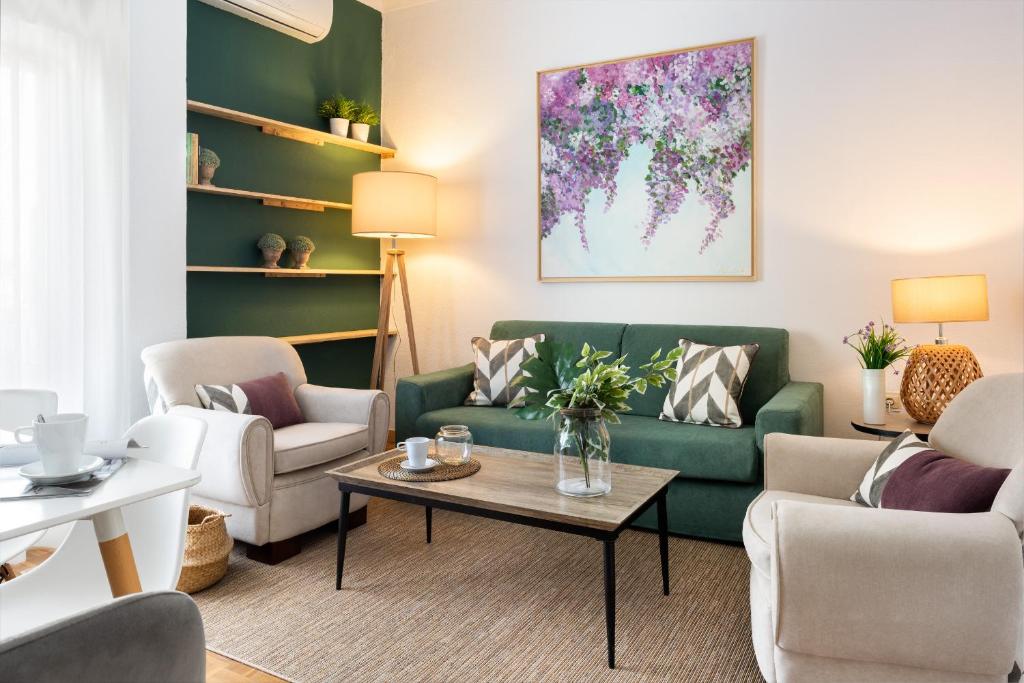 sala de estar con sofá verde y sillas en Magno Apartments Asunción, en Sevilla