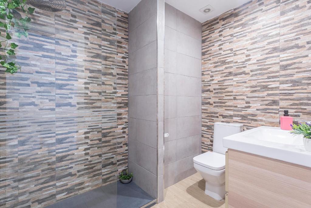 łazienka z toaletą i kamienną ścianą w obiekcie Luxe Vista Histórico 5 rooms 4 baños w mieście Jerez de la Frontera
