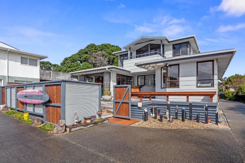 a house with a garage in front of it at Kiwiana Bach - Waihi Beach Holiday Home in Waihi Beach