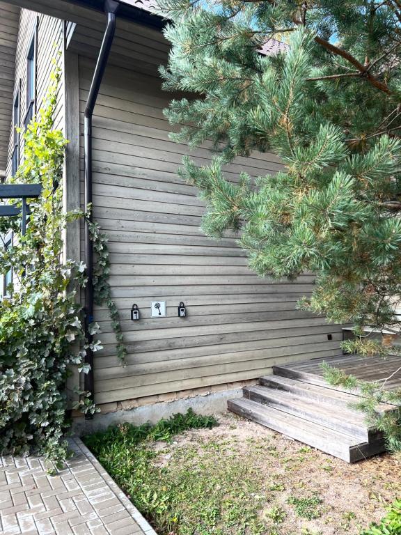 a house with a wooden wall with stairs on it at Rugio namai-Rye house in Palanga