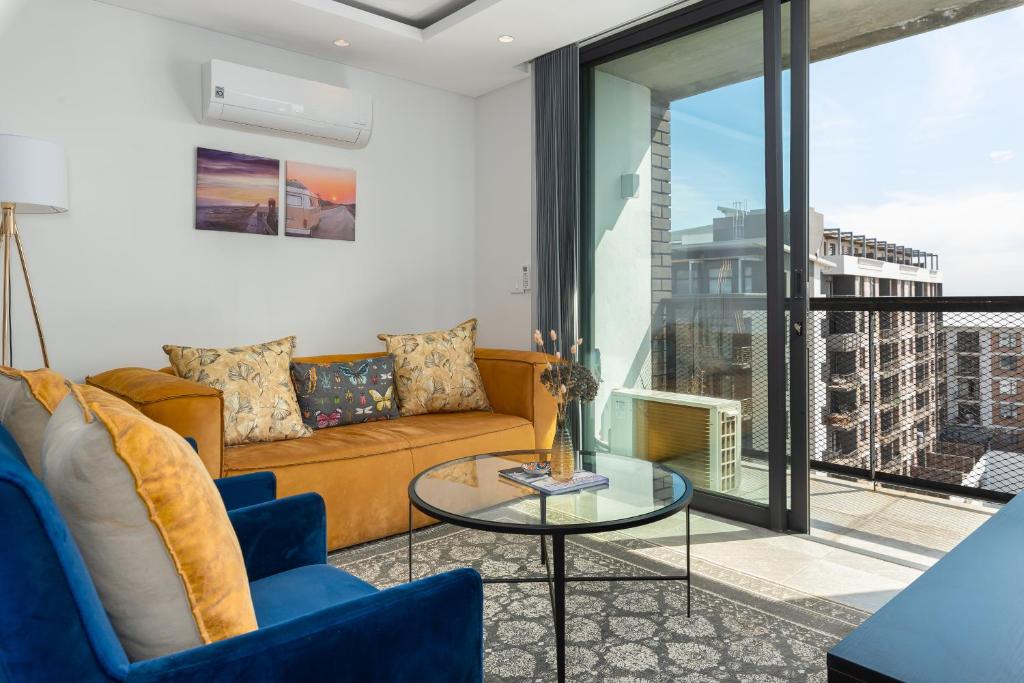 The Iron Works Apartments في كيب تاون: غرفة معيشة مع أريكة وطاولة زجاجية