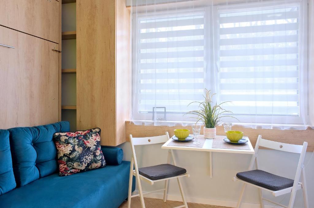 a living room with a blue couch and a table at Pokój 24E in Sobieszewo