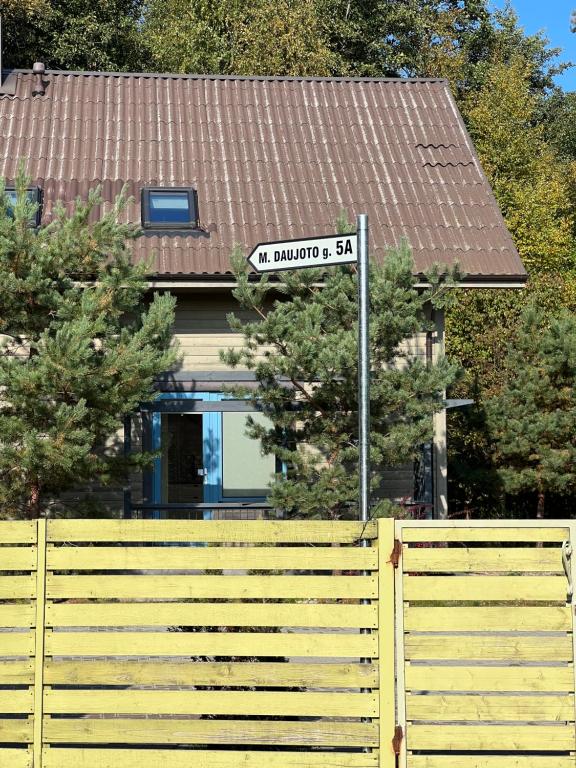 a street sign in front of a house with a fence at Rugio namai-Rye house in Palanga