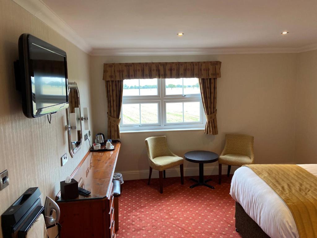 a hotel room with a bed and a television at Loftsome Bridge Hotel in Wressell