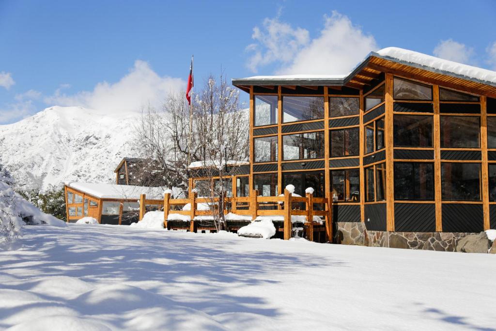 un bâtiment dans la neige avec une montagne dans l'établissement MI Lodge Las Trancas Hotel & Spa, à Las Trancas