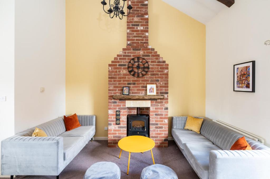 a living room with two couches and a brick fireplace at Pass the Keys Charming Cottage near Clifton Moor in York