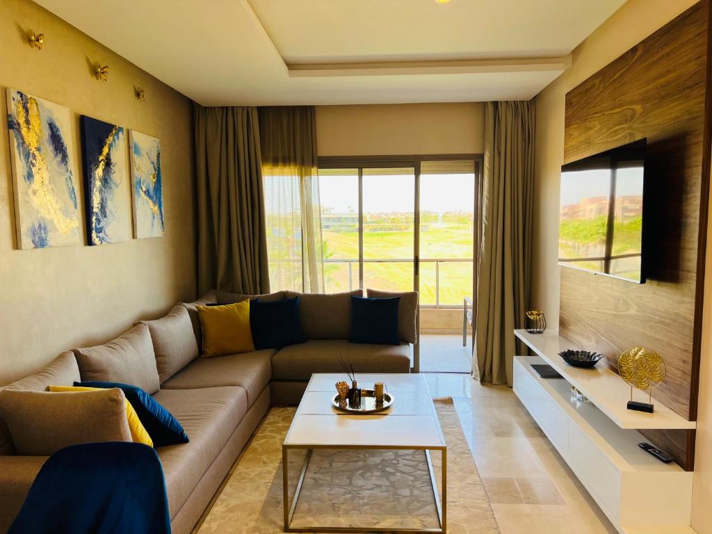 ein Wohnzimmer mit einem Sofa und einem Tisch in der Unterkunft Agate 212 Lovely 2-bedrooms apartment with pool & golf view in Marrakesch