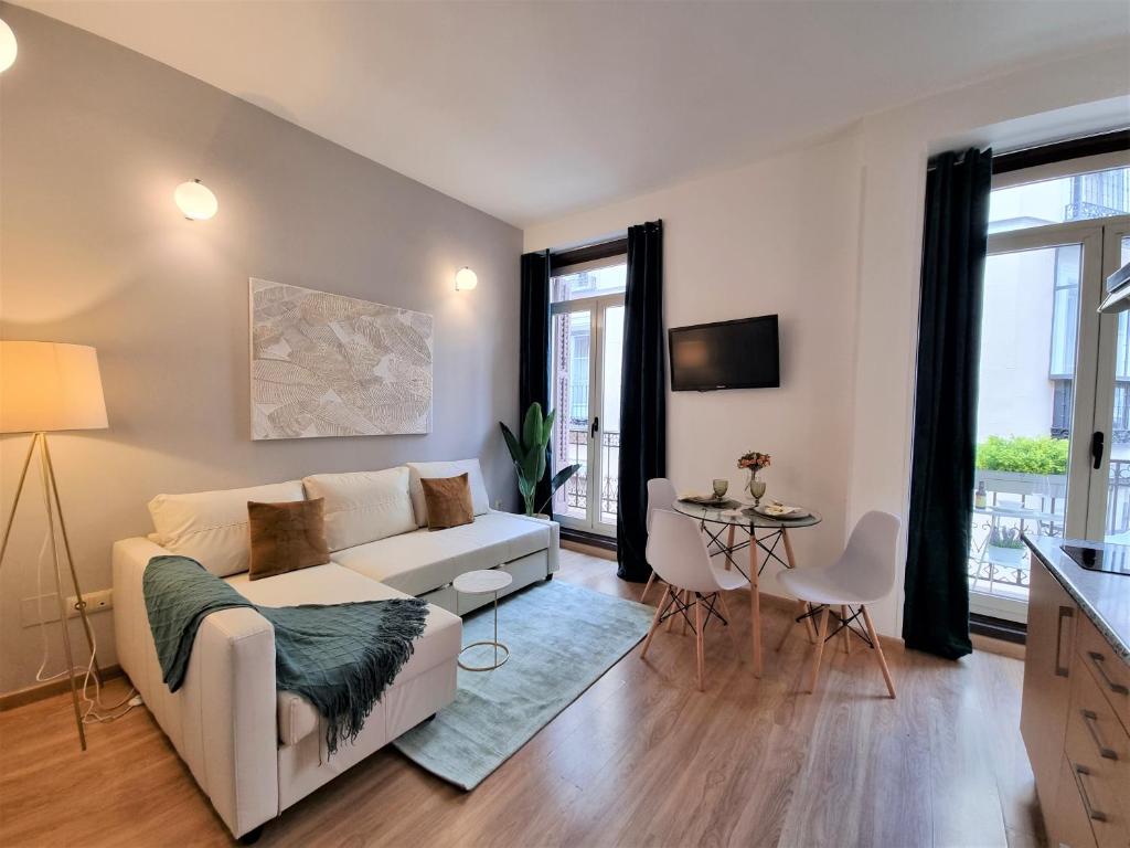 sala de estar con sofá blanco y mesa en Apartamentos San Isidro, en Madrid