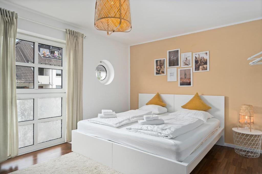 um quarto branco com uma grande cama branca e uma janela em Entspanntes Wohnen in Düren em Düren - Eifel