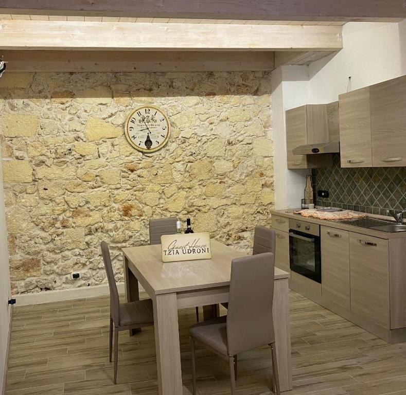 una cocina con mesa y sillas y un reloj en la pared en GUEST HOUSE TZIA UDRONI, en Ossi