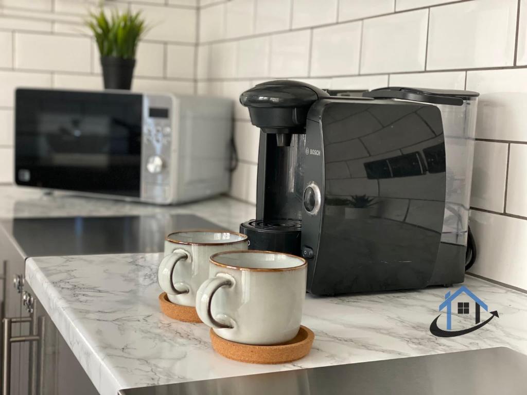 two coffee cups sitting on a counter next to a toaster at Acaster House, Rooms 1 to 5, free parking, SUPER fast wi-fi, en-suite, corporates welcome in Kettering