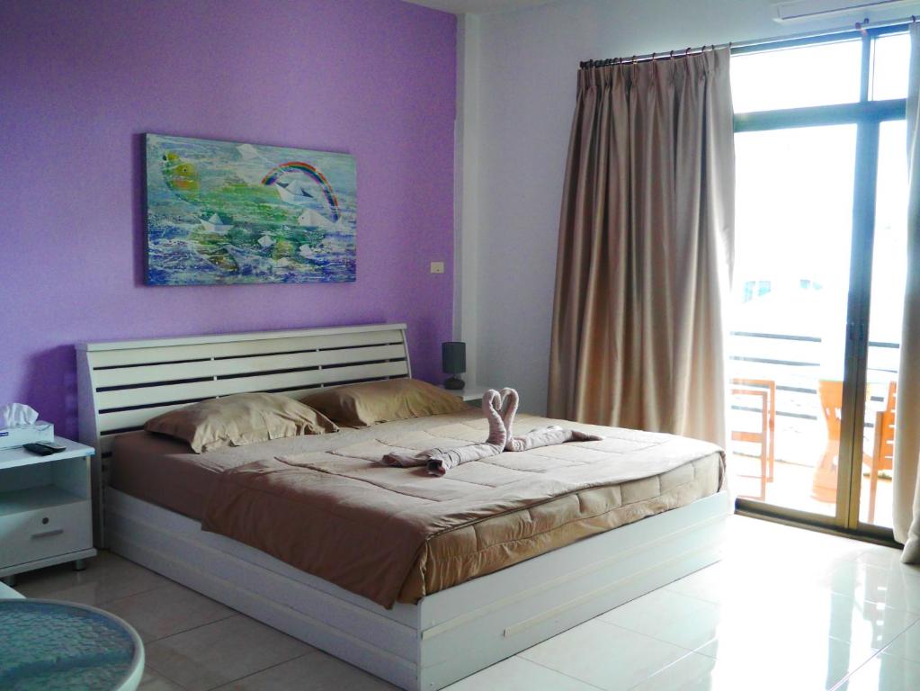 a bedroom with a bed with purple walls and a window at Da Puccio Rawai Guesthouse in Rawai Beach