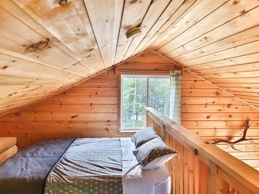 pokój z łóżkiem w drewnianym domku w obiekcie Juniper Cabin- Waterfront retreat on Mosque Lake w mieście Ompah