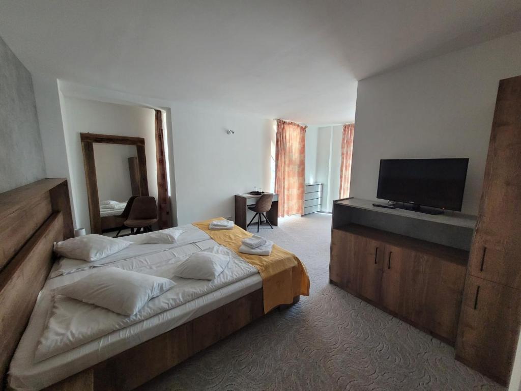 a bedroom with a large bed and a flat screen tv at Hotel City Center in Braşov