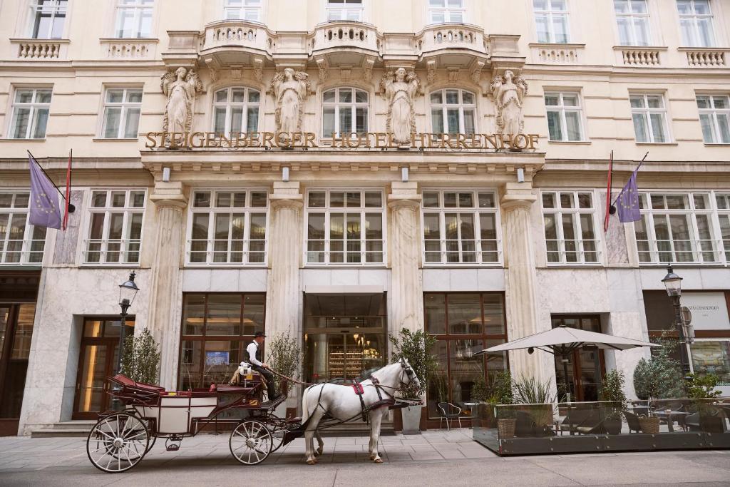 two horses pulling a carriage in front of a building at Steigenberger Hotel Herrenhof in Vienna
