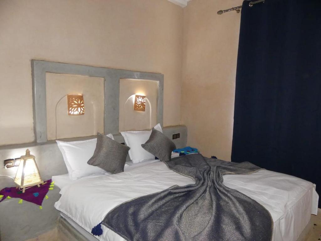 ein Schlafzimmer mit einem großen Bett mit weißer Bettwäsche und Kissen in der Unterkunft Dar Diafa Chez Anaam in Er Rachidia