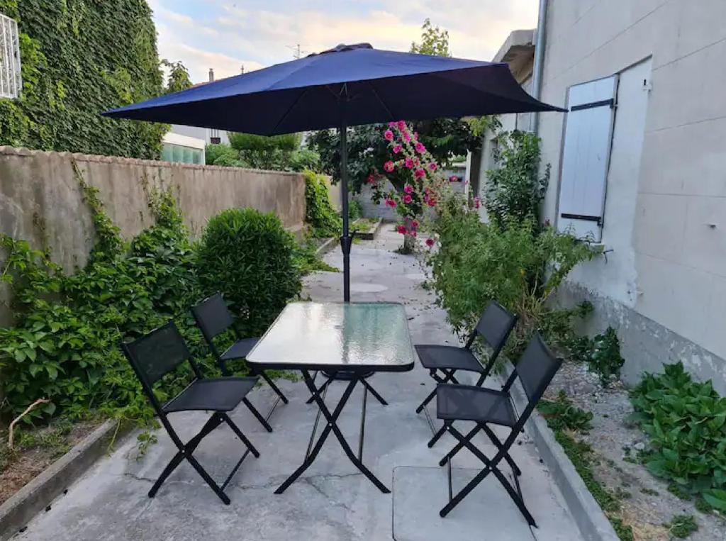 une table et des chaises avec un parasol sur une terrasse dans l'établissement T2 Centre ville avec jardin, à Arles