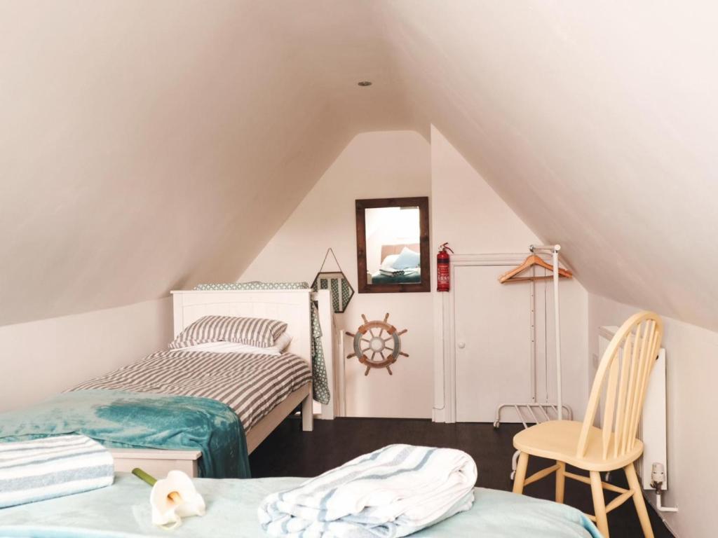 a attic bedroom with two beds and a chair at Nannys Nook whitstable kent in Whitstable