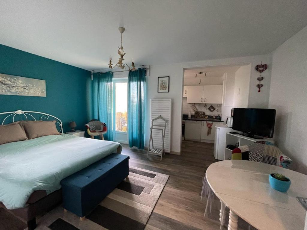 a bedroom with a bed and a table and a kitchen at La Colonne in Obernai