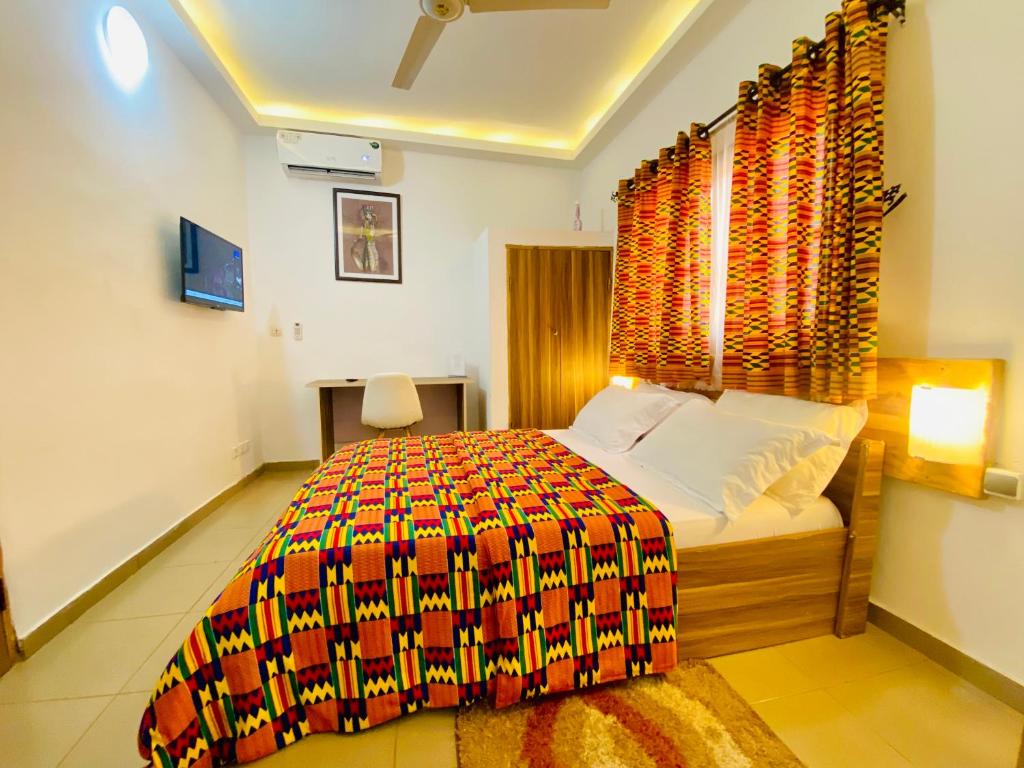 a bedroom with a bed with a colorful bedspread at GRACE LODGE in Lomé