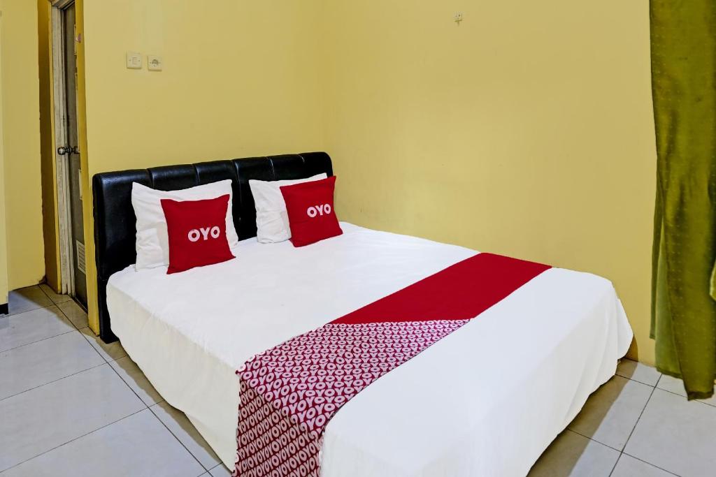 a bedroom with a bed with red pillows on it at OYO 91795 Kos Jeehel Syariah in Sidoarjo