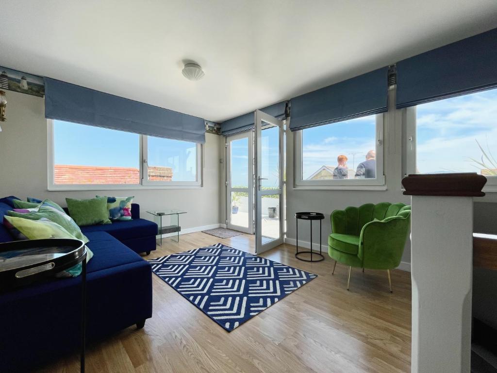 uma sala de estar com um sofá azul e cadeiras verdes em 2 bedr apmt, seaview terrace, central Broadstairs em Broadstairs