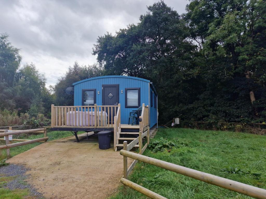 a blue trailer in a field next to a fence at Glamping Hut - Sleeps up to 4 Hot Tub & Parking in Welshpool