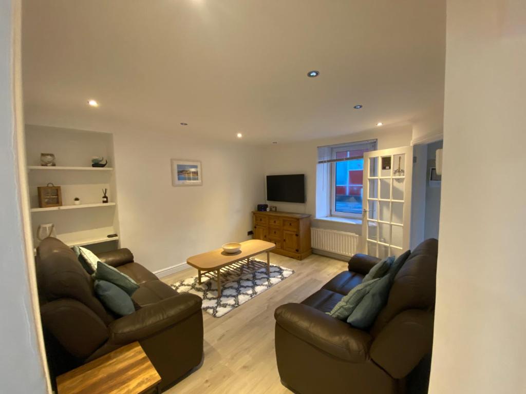 a living room with two couches and a table at Sands Reach, dog friendly Tenby house in Tenby