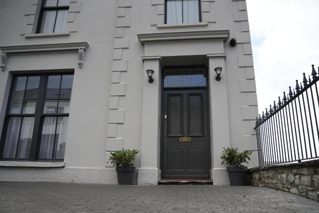 een zwarte deur op een wit gebouw met potplanten bij Immaculate 1-Bed Apartment in Merthyr Tydfil in Merthyr Tydfil