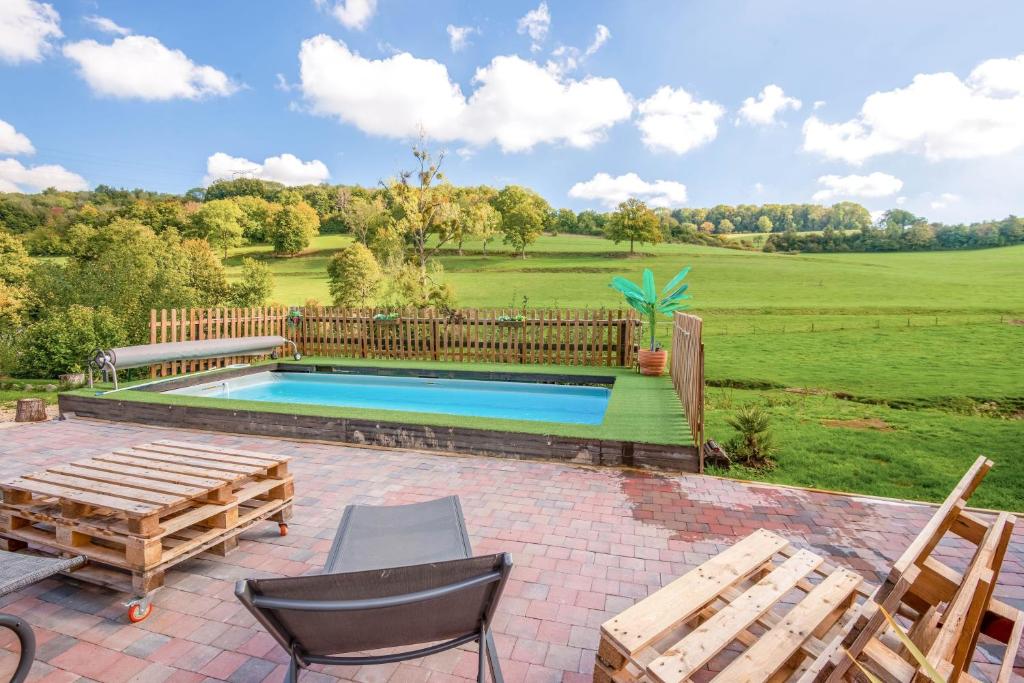 a swimming pool with a wooden fence and chairs at Villa de 2 chambres avec piscine privee jardin clos et wifi a Sapogne et Feucheres in Sapogne-et-Feuchères