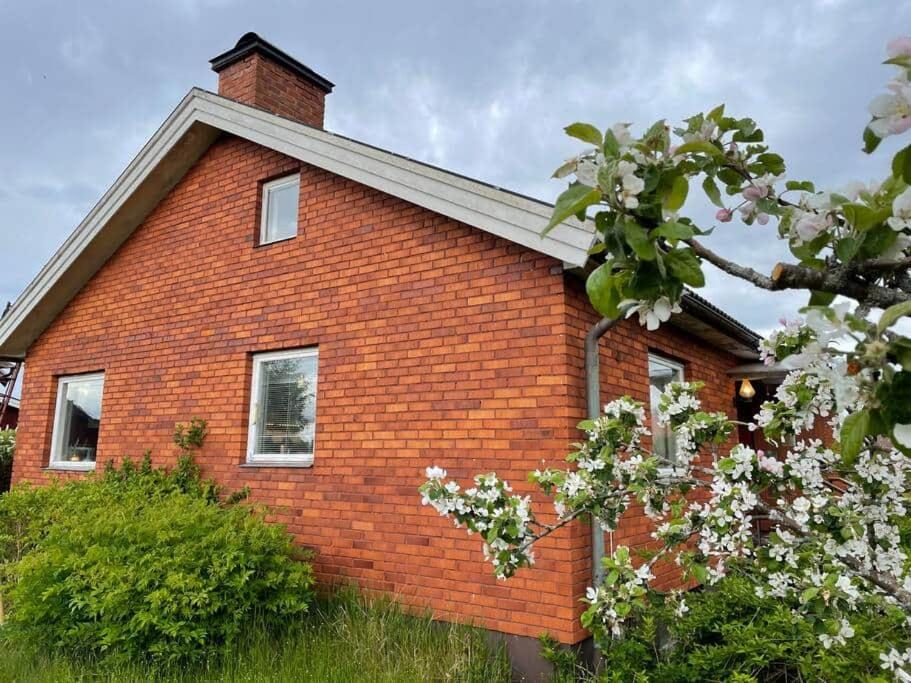 una casa de ladrillo rojo con flores blancas delante de ella en Homestay in picturesque village, 