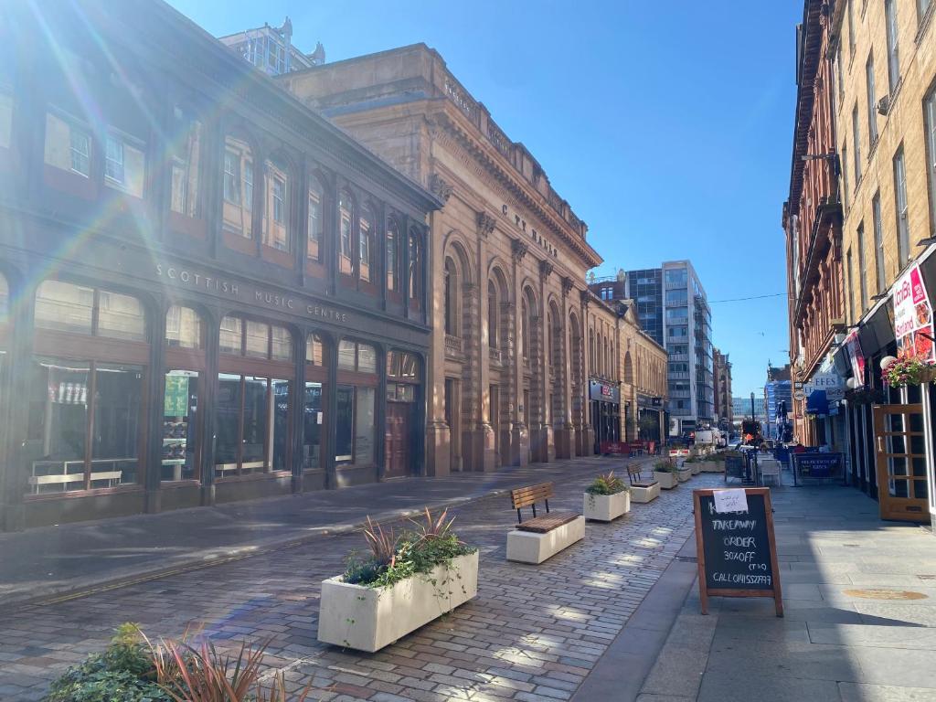an empty city street with buildings and a sign at Lovely 1-Bed Apartment in Glasgow Merchant City in Glasgow